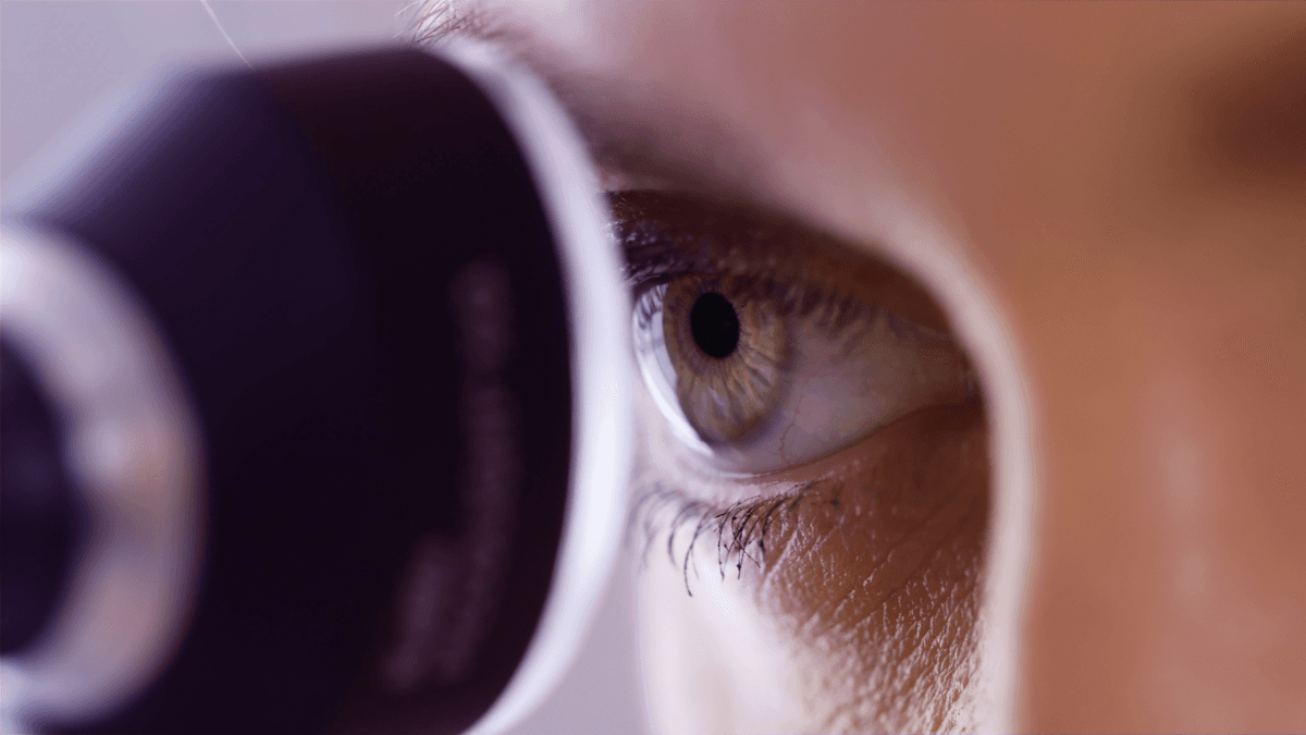Close-up of an eye looking into a medical diagnostic device.